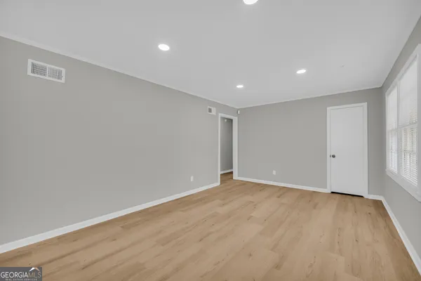 an empty room with wooden floor and windows