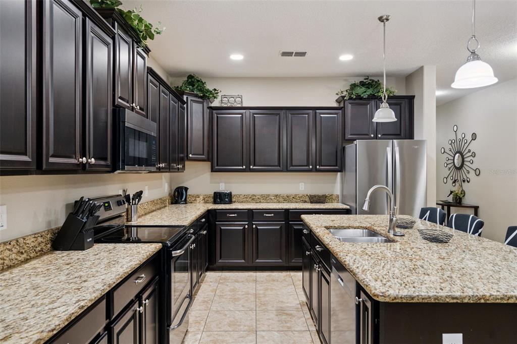 8965 Cuban Palm Road Kissimmee, FL 34747 - Photo 12 of 77 a kitchen with granite countertop a sink a counter top space appliances and cabinets