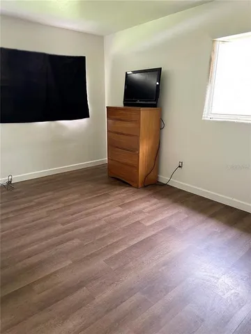 a view of room with wooden floor and flat screen tv