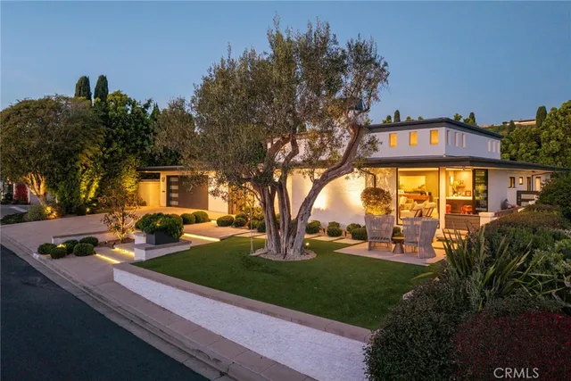 a front view of a house with garden and trees