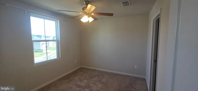 an empty room with window chandelier fan