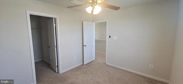 an empty room with closet and a chandelier fan