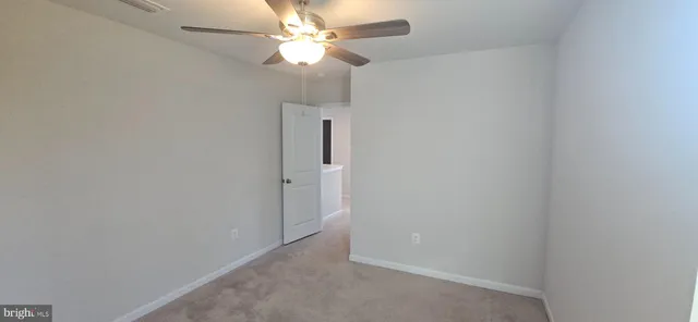 an empty room with a fan & a ceiling fan