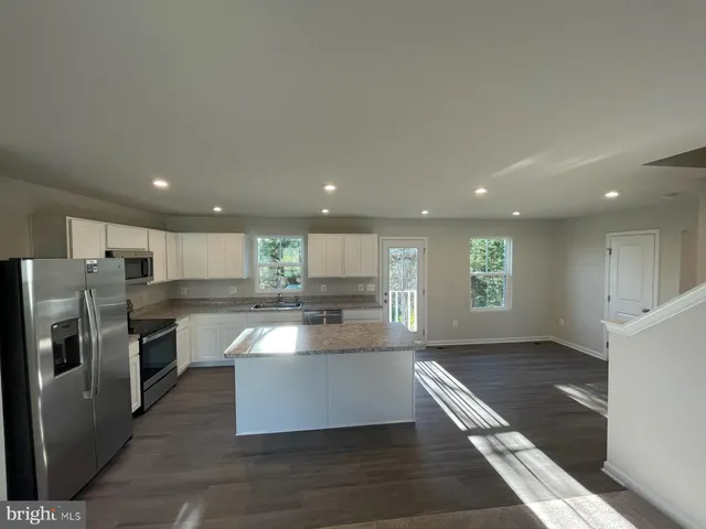 a kitchen with stainless steel appliances granite countertop a refrigerator a sink a stove and a oven