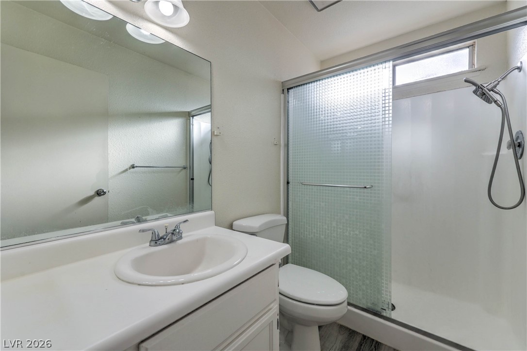 581 Carleton Drive Henderson, NV 89014 - Photo 16 of 37 A streamlined primary bathroom with a spacious vanity, toilet, and a glass-enclosed shower.