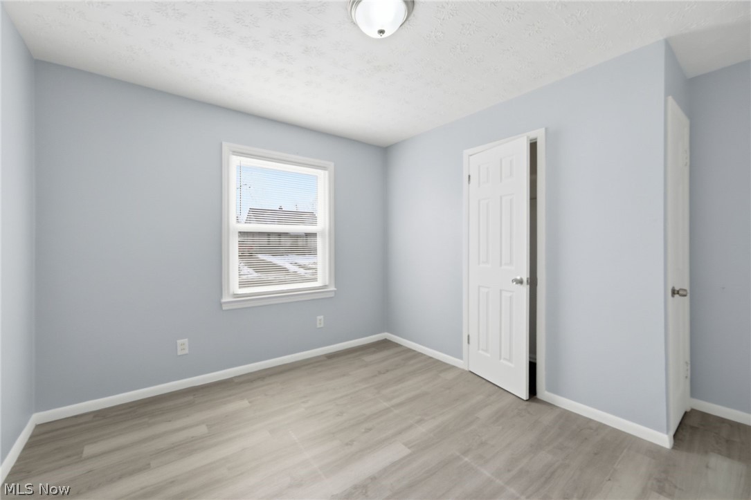 20705 Hansen Road Maple Heights, OH 44137 - Photo 14 of 24 Unfurnished bedroom with a closet, light wood finished floors, and a textured ceiling