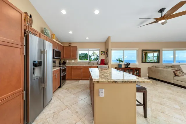 a kitchen with stainless steel appliances kitchen island granite countertop a refrigerator and a stove top oven