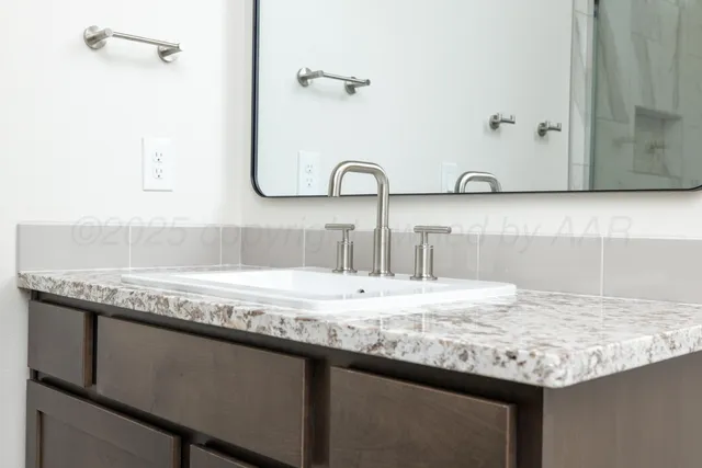 a bathroom with a granite countertop sink and a mirror
