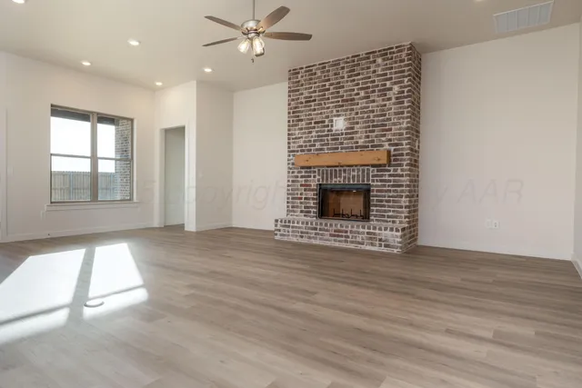 an empty room with wooden floor fireplace and windows