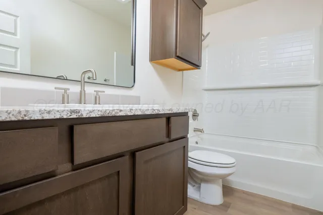 a bathroom with a granite countertop toilet sink and mirror