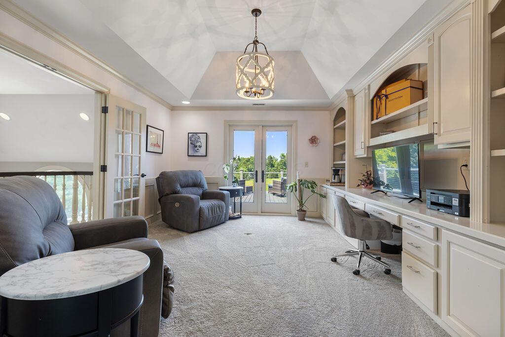 2570 Jewett Road Powell, OH 43065 - Photo 44 of 104 • Grey carpet • Pink painted & wainscoted walls • Built-in bookcases • Tray ceiling • Chandelier • French doors to Juliet balcony • French doors to composite deck
