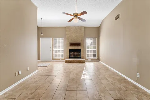 a view of a livingroom with a fireplace a ceiling fan and window
