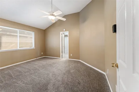 an empty room with a chandelier fan and windows