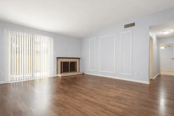 an empty room with wooden floor fireplace and windows