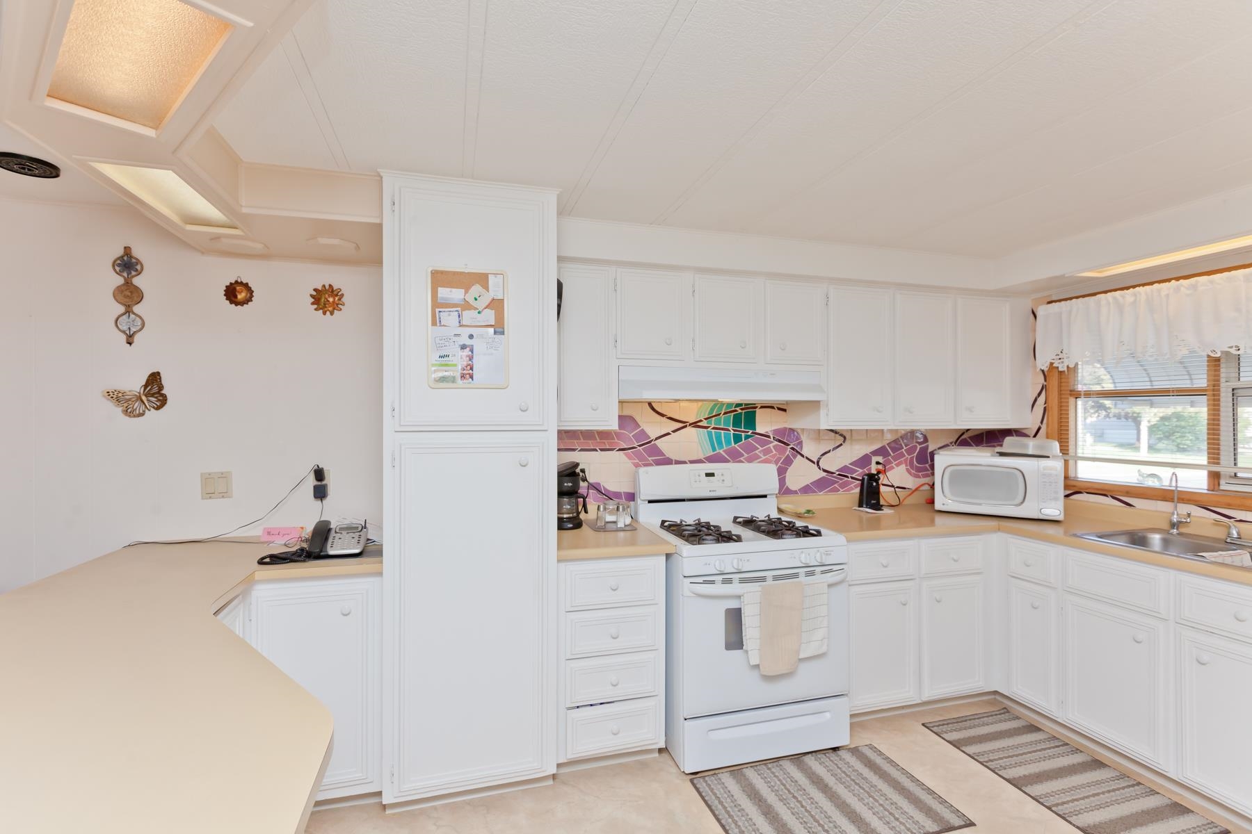 3251 E Road, Unit 20 Clifton, CO 81520 - Photo 12 of 26 a white kitchen with a refrigerator a stove a sink and white cabinets with wooden floor