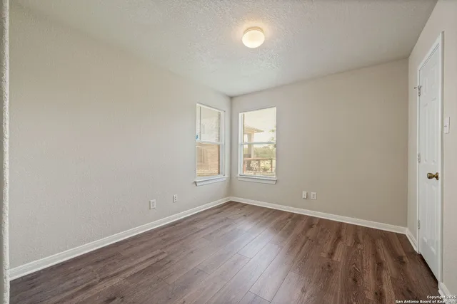 an empty room with wooden floor and windows