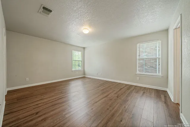 an empty room with wooden floor and windows