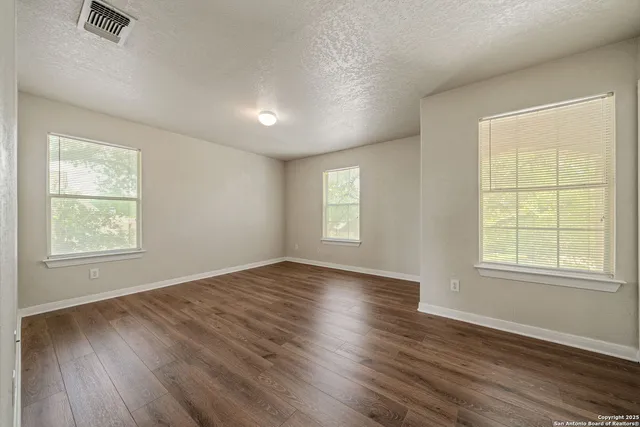 an empty room with wooden floor and windows