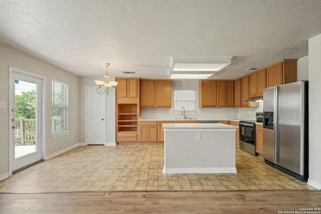 a kitchen with stainless steel appliances granite countertop a refrigerator a sink a stove and oven