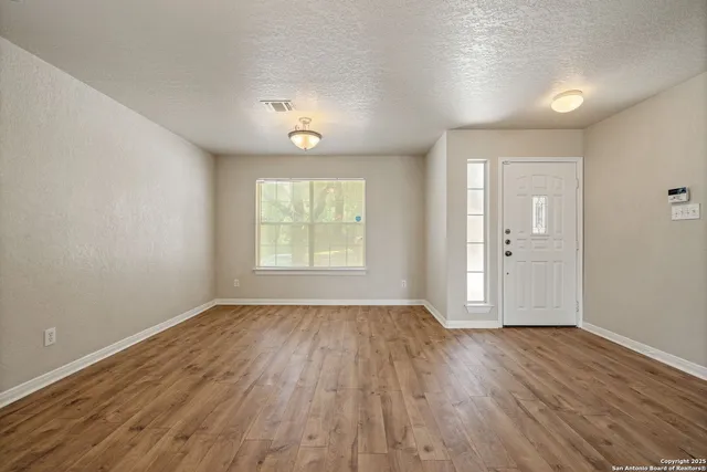 an empty room with wooden floor and windows