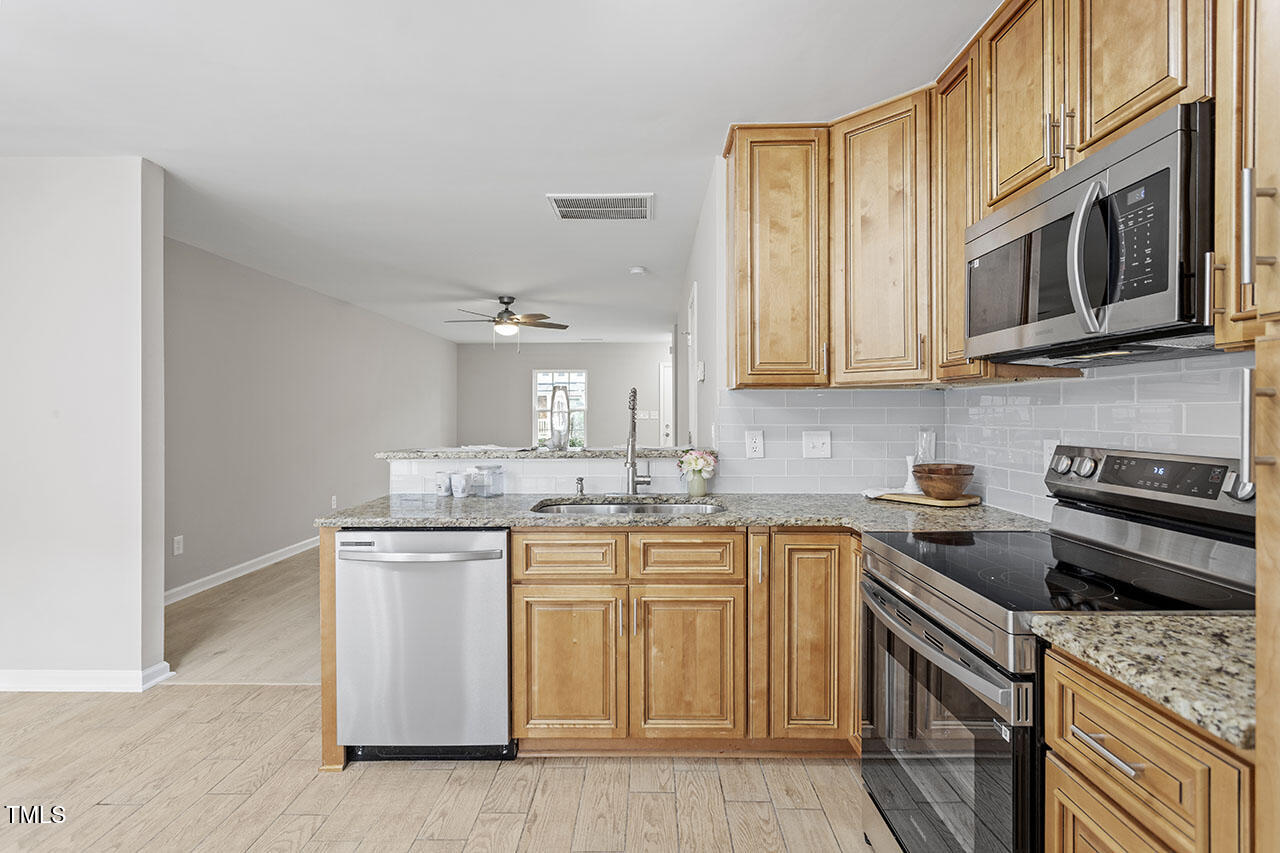 5340 Big Bass Drive Raleigh, NC 27610 - Photo 9 of 20 a kitchen with stainless steel appliances granite countertop a sink stove and microwave