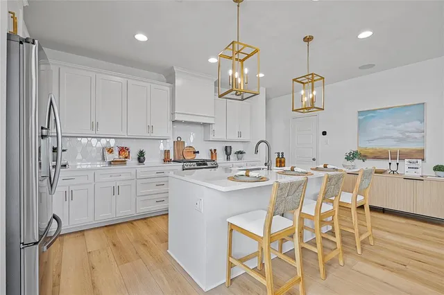 a kitchen with stainless steel appliances granite countertop a sink a stove and chairs with wooden floor