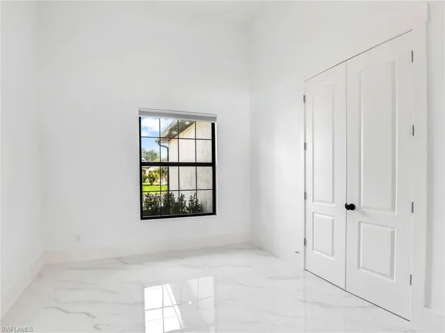 a bedroom with a bed a bookshelf and a large window