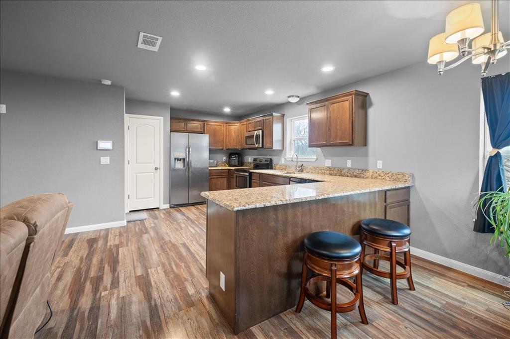 512 Alameda Road Azle, TX 76020 - Photo 7 of 28 a kitchen with stainless steel appliances granite countertop a microwave a stove a sink dishwasher and white cabinets with wooden floor