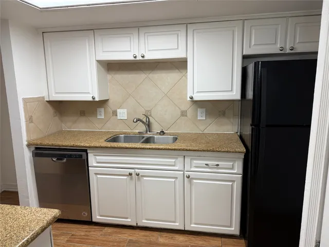 a kitchen with granite countertop white cabinets and refrigerator