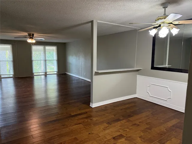 an empty room with wooden floor cabinet and windows