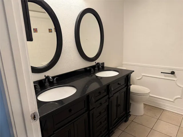 a bathroom with a granite countertop toilet a sink and a mirror