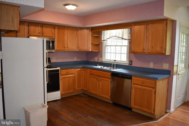 a kitchen with granite countertop wooden floors and white stainless steel appliances