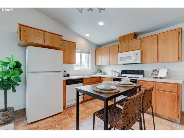 a kitchen with stainless steel appliances granite countertop a refrigerator a sink a stove and white cabinets