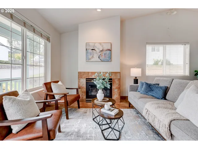 a living room with furniture a fireplace and large windows