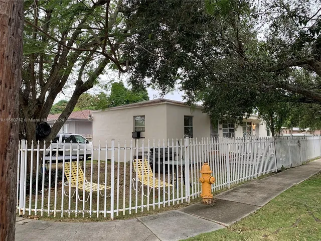 a view of a house with a small yard and a large tree