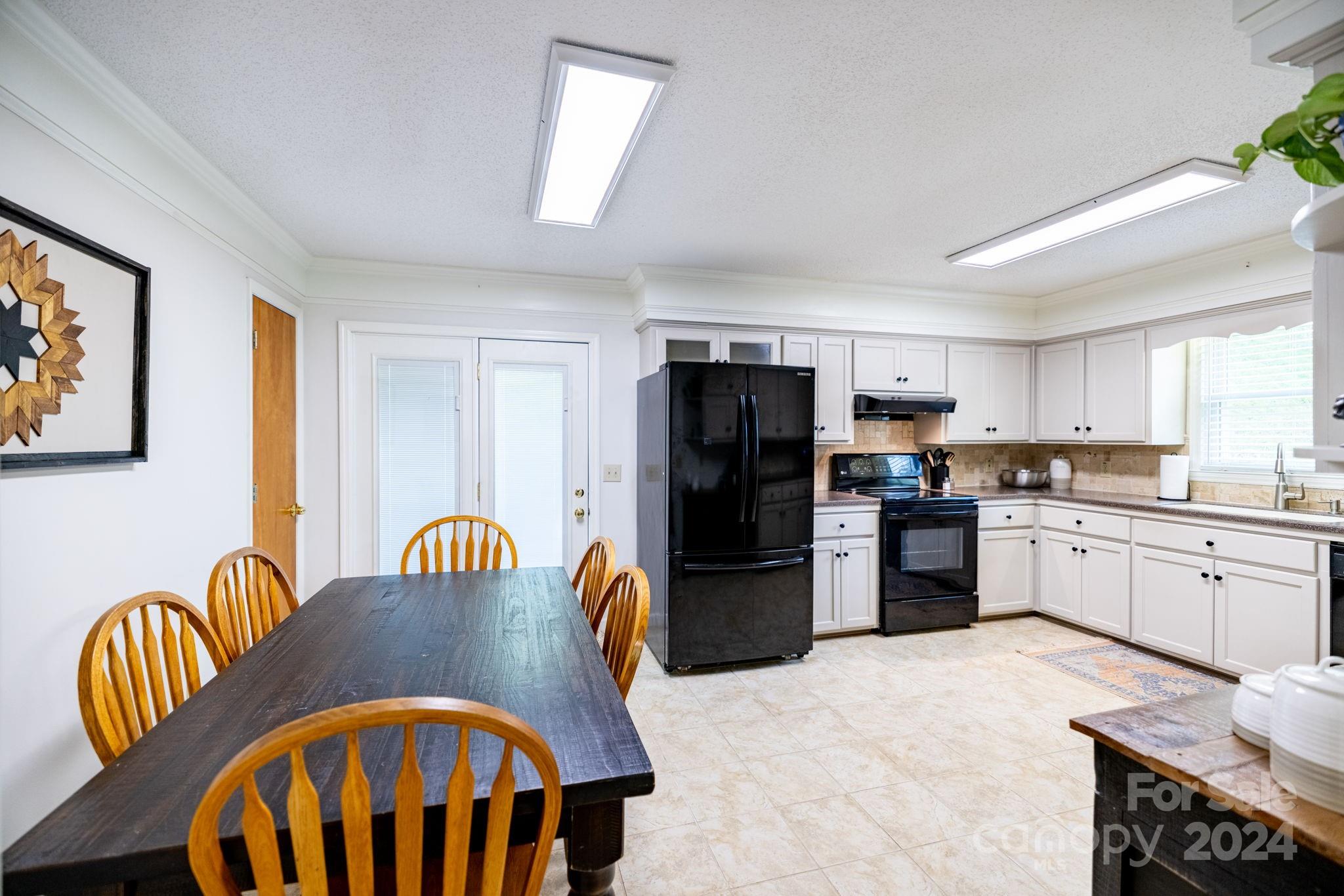 779 Silas Creek Road, Unit 17 & 18 Lansing, NC 28643 - Photo 6 of 35 a kitchen with stainless steel appliances kitchen island granite countertop a refrigerator a stove a sink dishwasher with a dining table and chairs