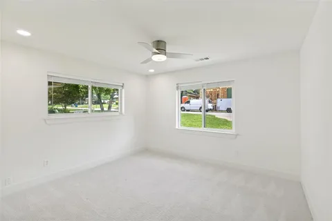an empty room with windows and a ceiling fan