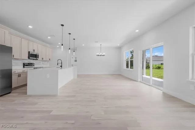 a view of a kitchen with a sink and dishwasher a refrigerator with white cabinets