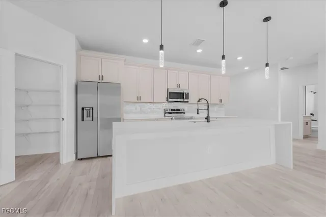 a view of a kitchen with a sink a refrigerator and cabinets