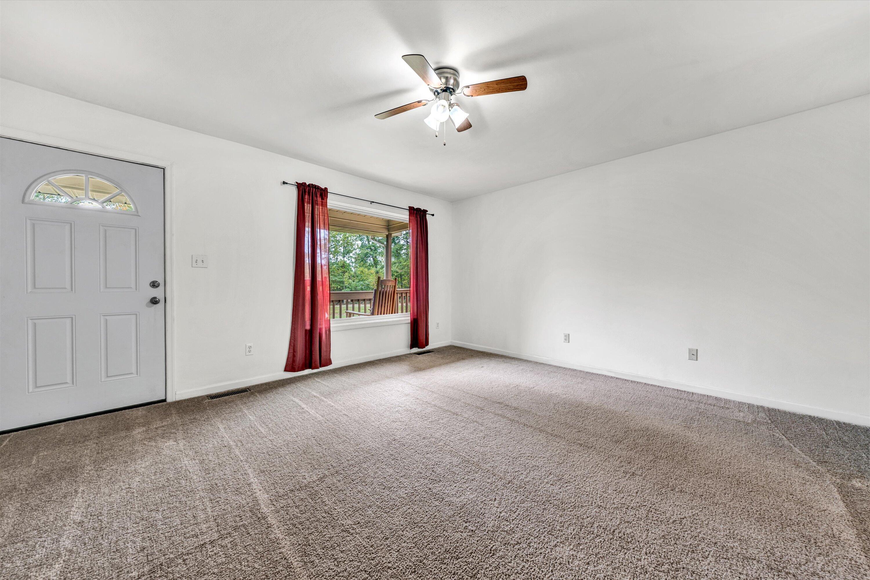 4291 Mill Iron Road Goodview, VA 24095 - Photo 7 of 33 an empty room with a ceiling fan and windows