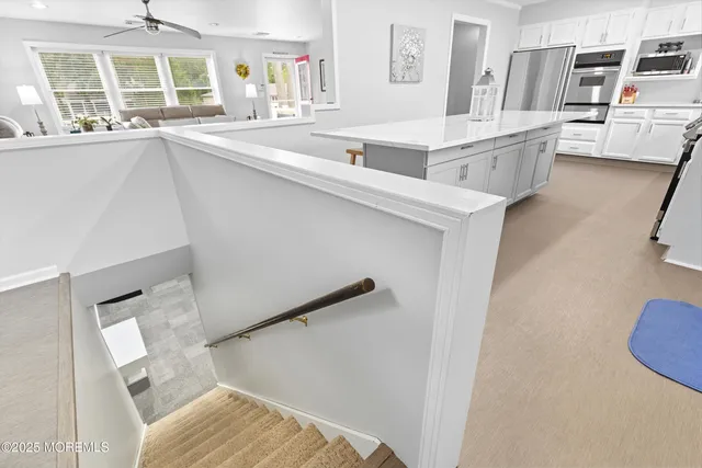 a living room with couches and kitchen view with wooden floor