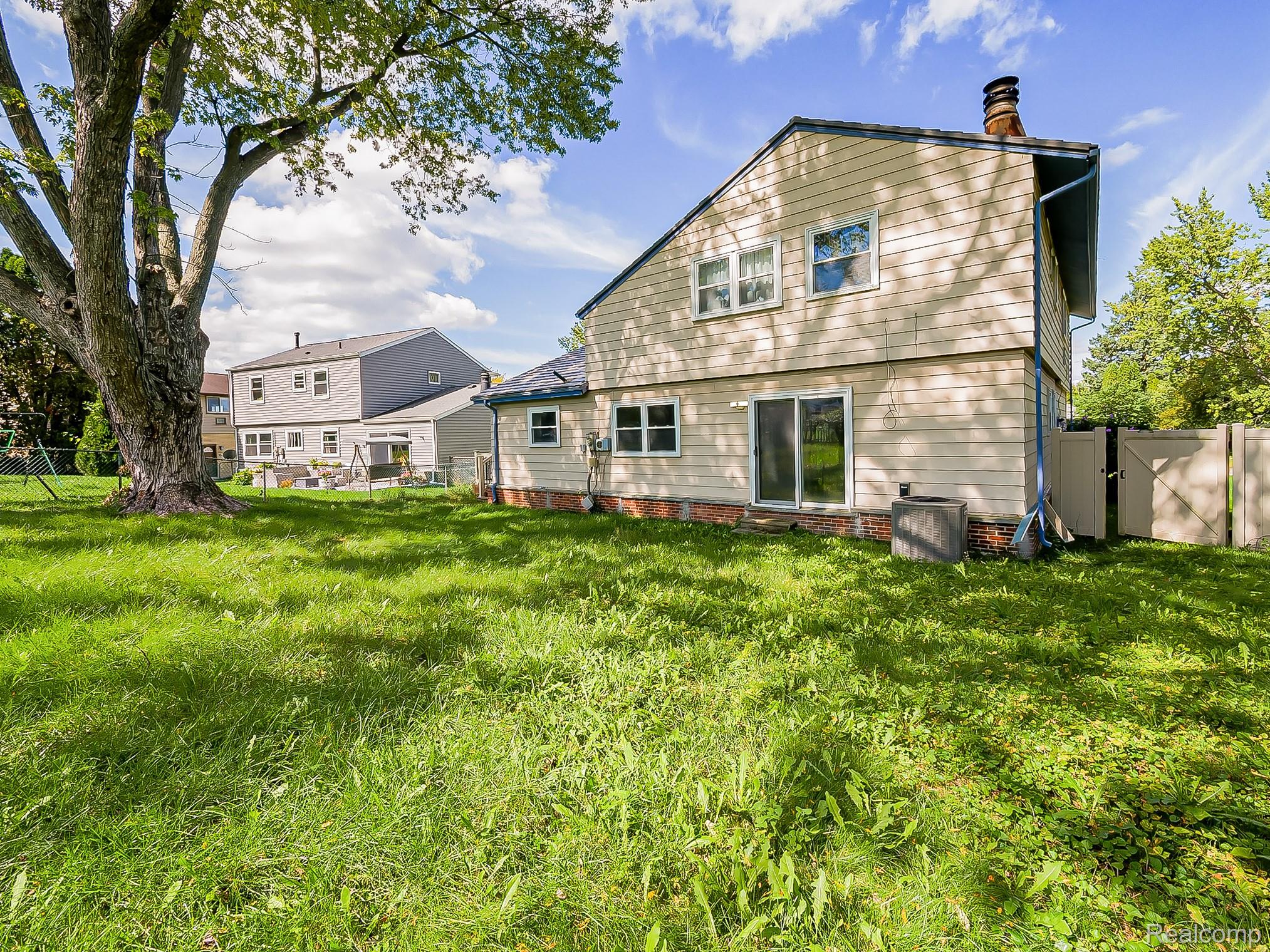 42195 Park Ridge Road Novi, MI 48375 - Photo 45 of 52 Expansive grass yard with mature tree, siding exterior, sliding glass door, and fenced area