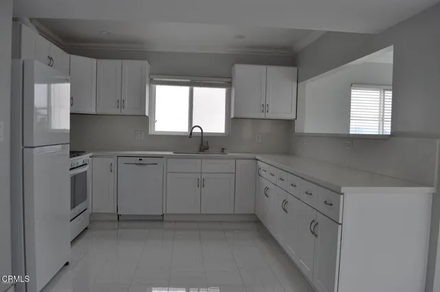 a kitchen with cabinets appliances a sink and a window