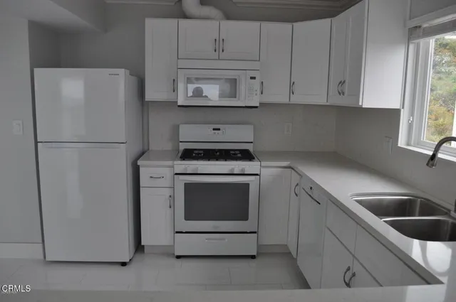 a kitchen with refrigerator a stove a sink and cabinets