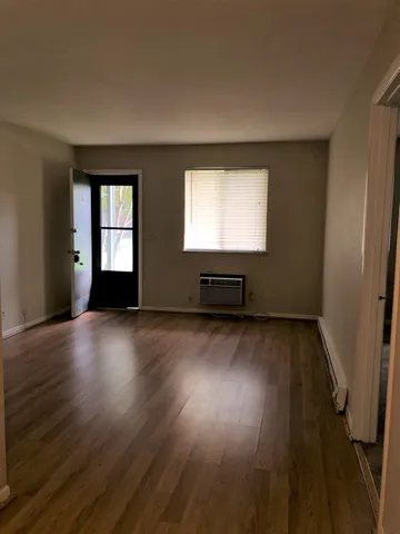 a view of an empty room with wooden floor and a window