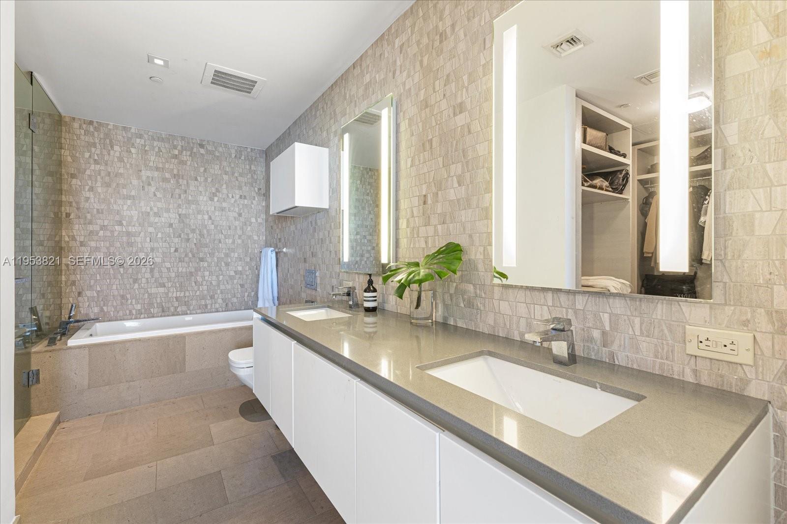 88 Southwest 7th Street, Unit 2506 Miami, FL 33130 - Photo 15 of 32 a bathroom with a granite countertop sink a large mirror and a bathtub