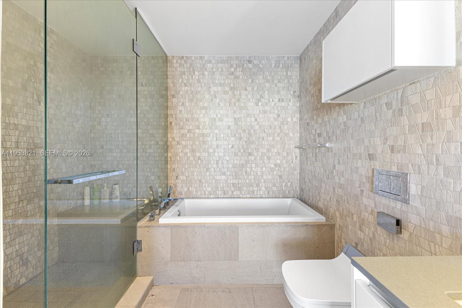 88 Southwest 7th Street, Unit 2506 Miami, FL 33130 - Photo 16 of 32 a bath tub sitting next to a white toilet and a shower