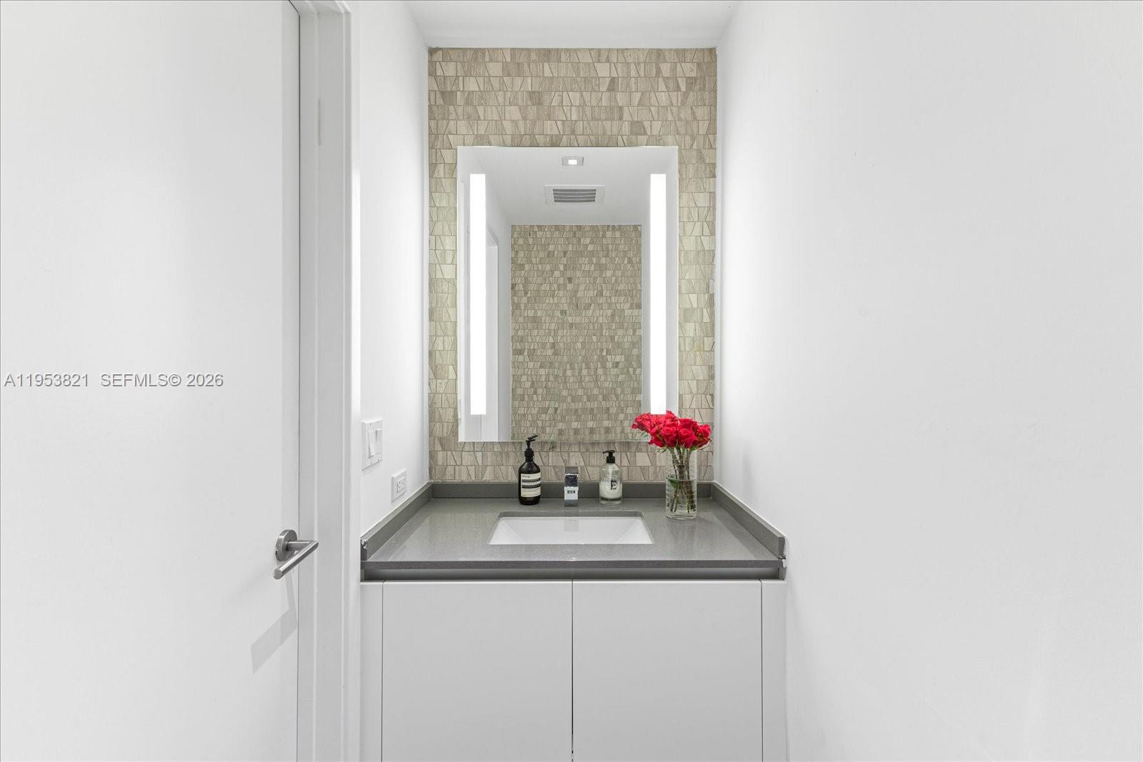 88 Southwest 7th Street, Unit 2506 Miami, FL 33130 - Photo 19 of 32 a bathroom with a granite countertop sink and a mirror