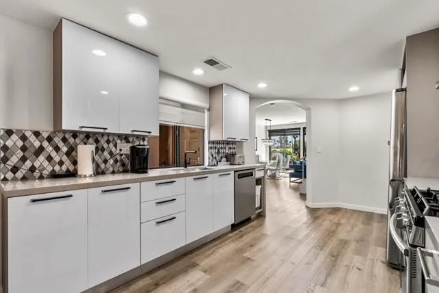 a kitchen with white cabinets and sink