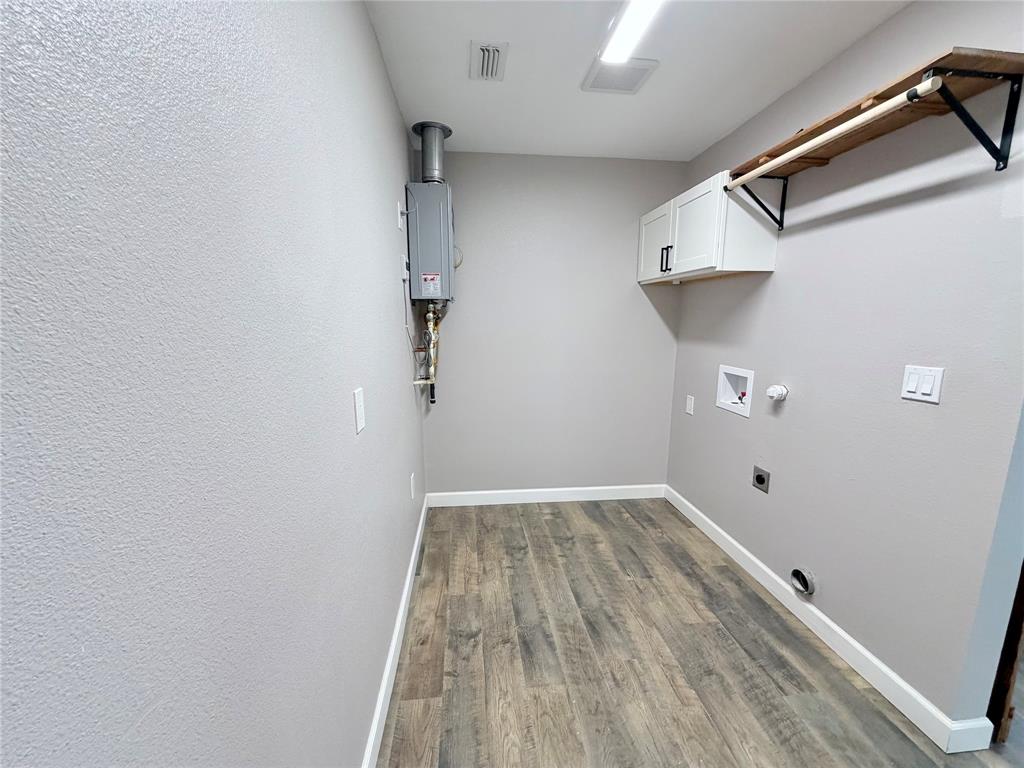 710 North Rusk Street Weatherford, TX 76086 - Photo 15 of 30 large open utility area with full size w-d hookups, hanging rod, upper cabnit for stoage. tankless water heater is in this room. Plenty of room for a deep freezer